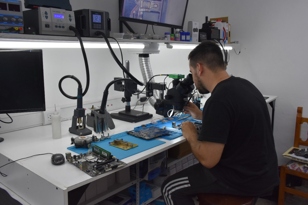Técnico de Clearsoft reparando una motherboard con microscopio en el laboratorio de Luis Guillón